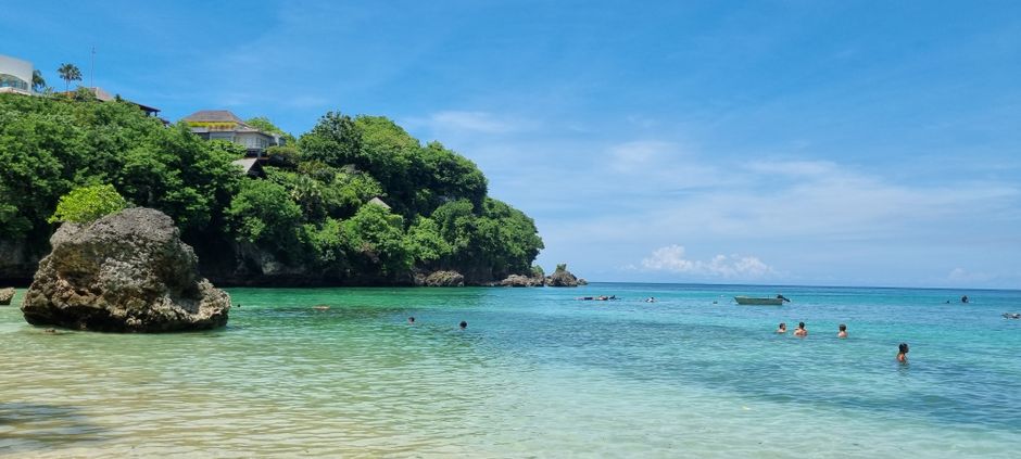 Idyllic tropical beach with lush greenery and clear blue waters.